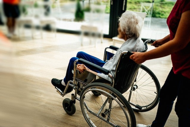 caregiver in nigeria wheeling an elderly